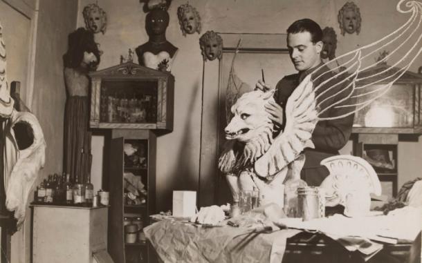 Oliver Messel in his studio painting a plaster griffin